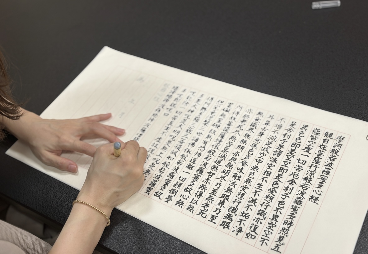 close-up of hands doing shakyo sutra copying with mindful focus in a Zen retreat setting