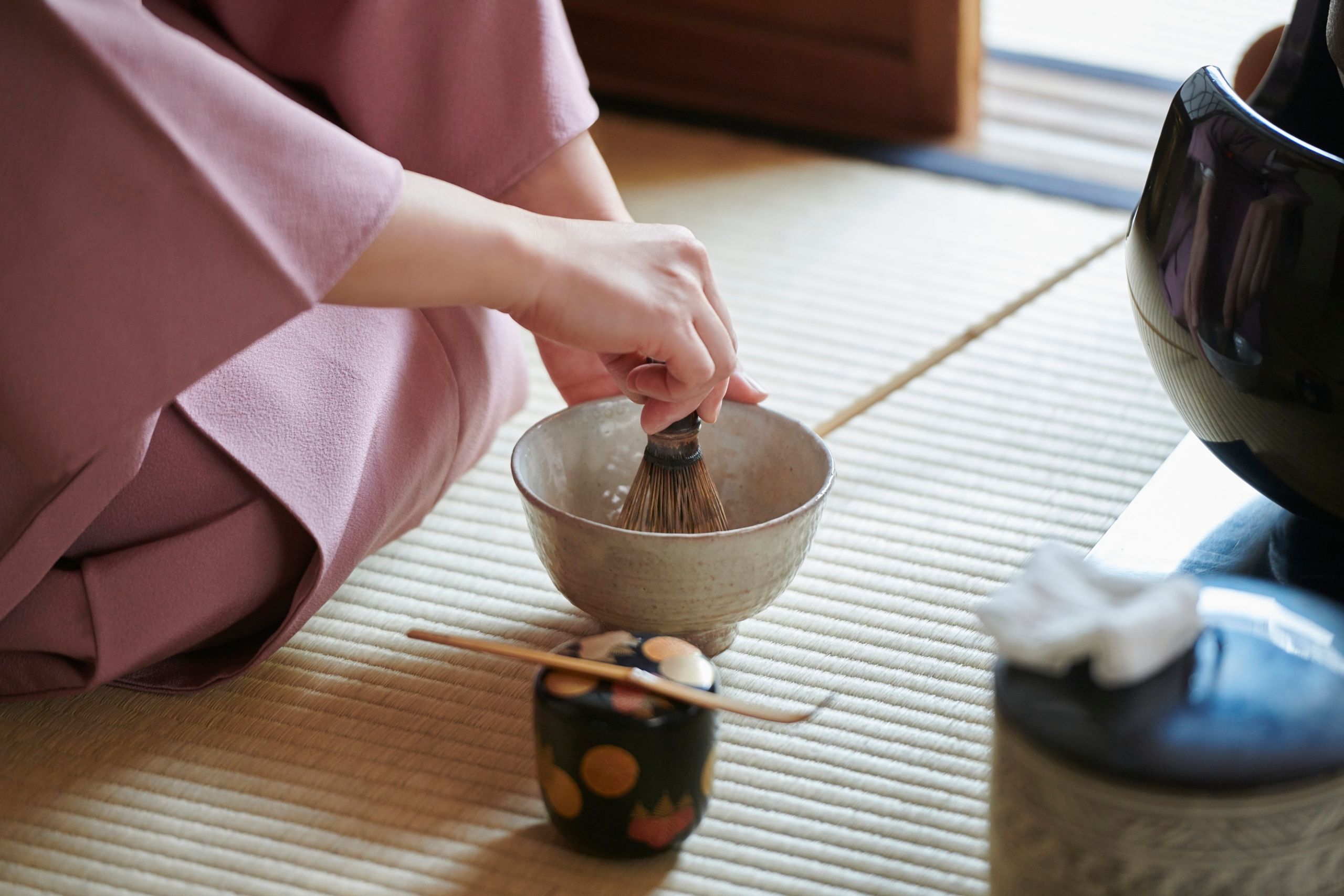 Close-up of hands whisking matcha during a Japanese tea ceremony, symbolizing stillness in mindful ritual at Buddhist retreats