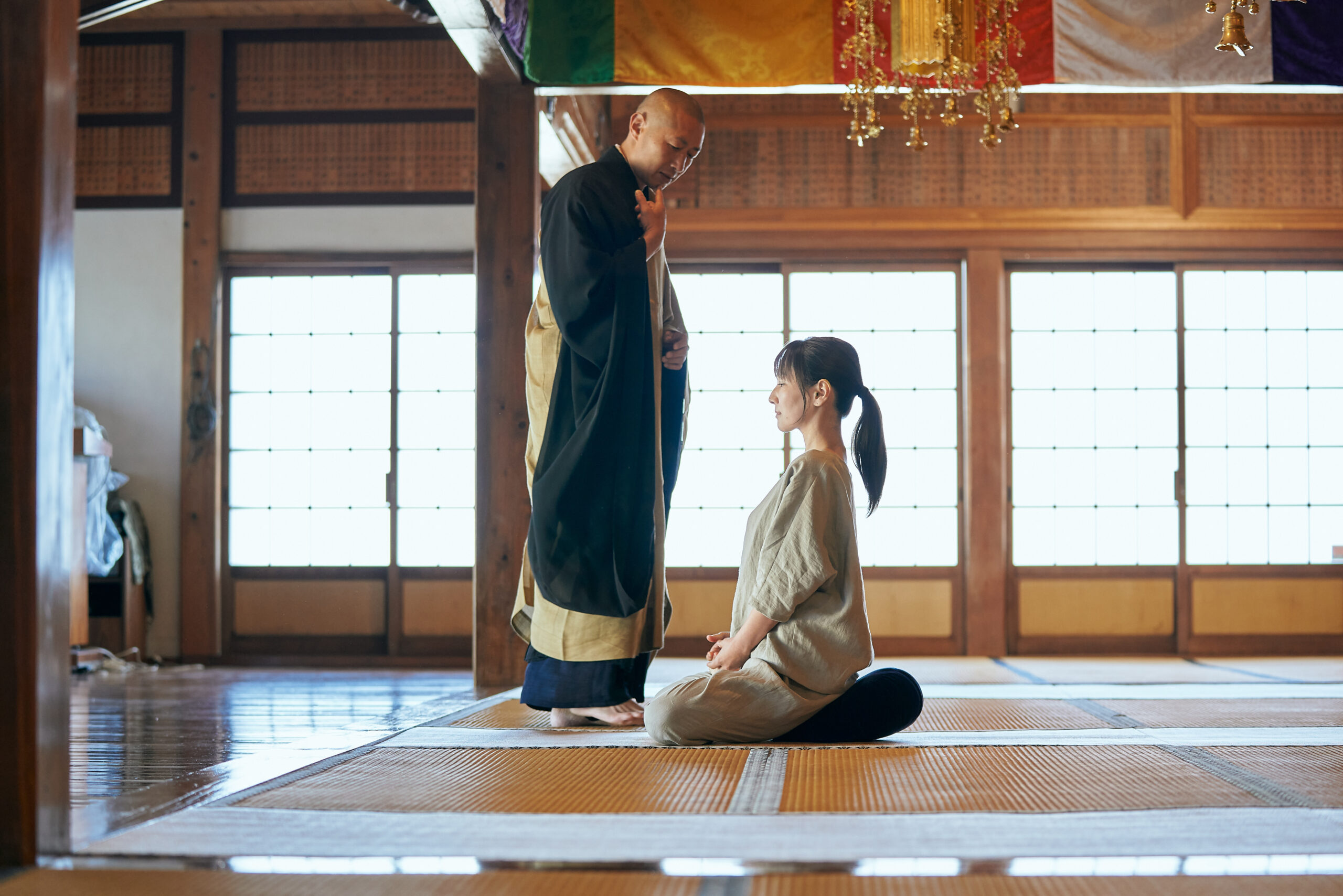 副住職が禅堂で坐禅の姿勢と呼吸法を説明している様子。参加者が静かに耳を傾けている。