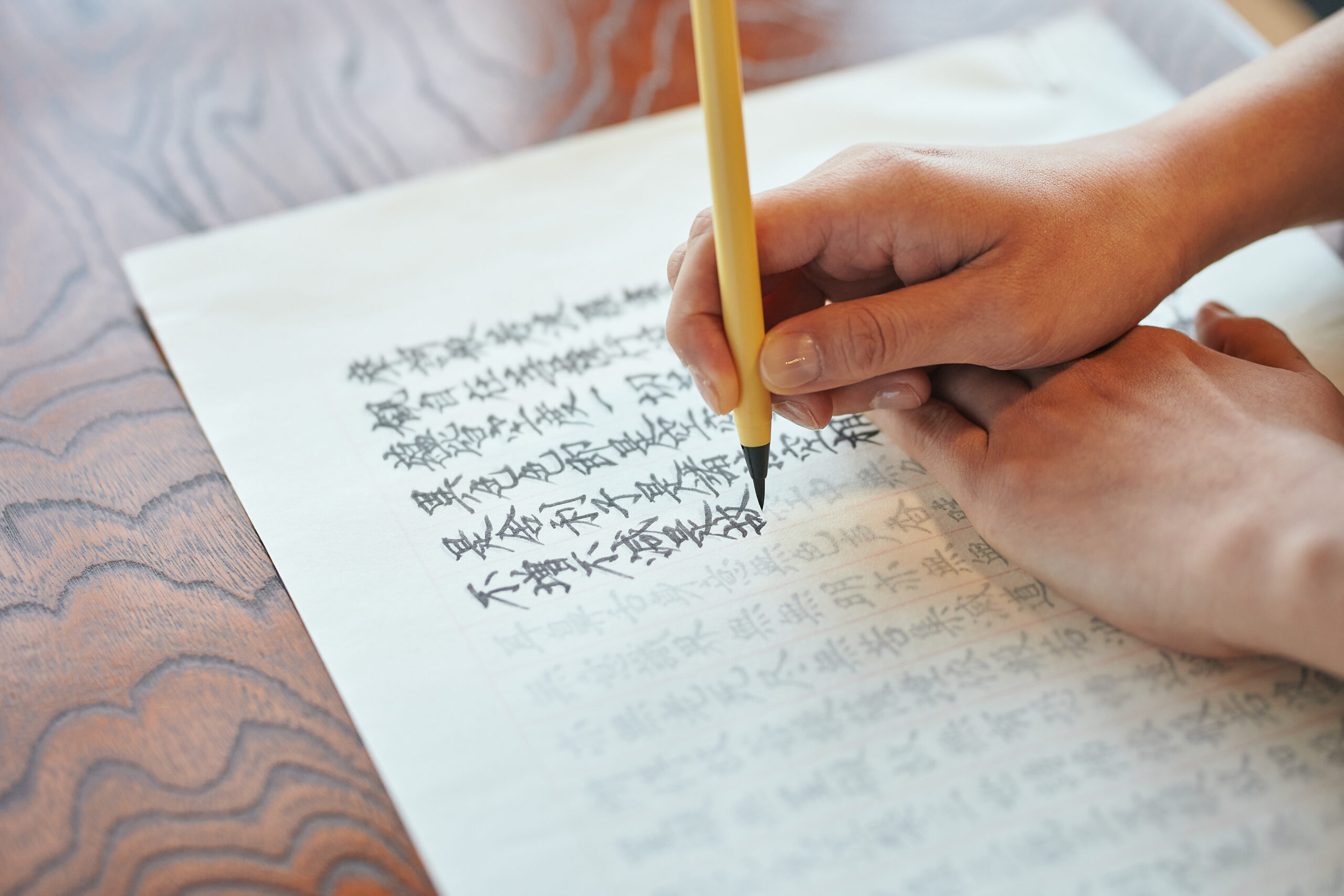 筆で経文を丁寧に写す手元。静かな集中と呼吸が伝わる瞬間。