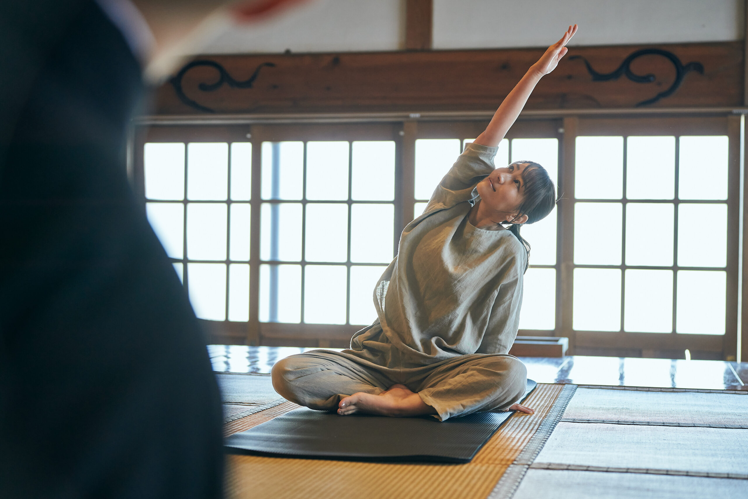 畳の上で静かに体を伸ばす女性。朝の光に包まれ、呼吸と動きがひとつになる瞬間。